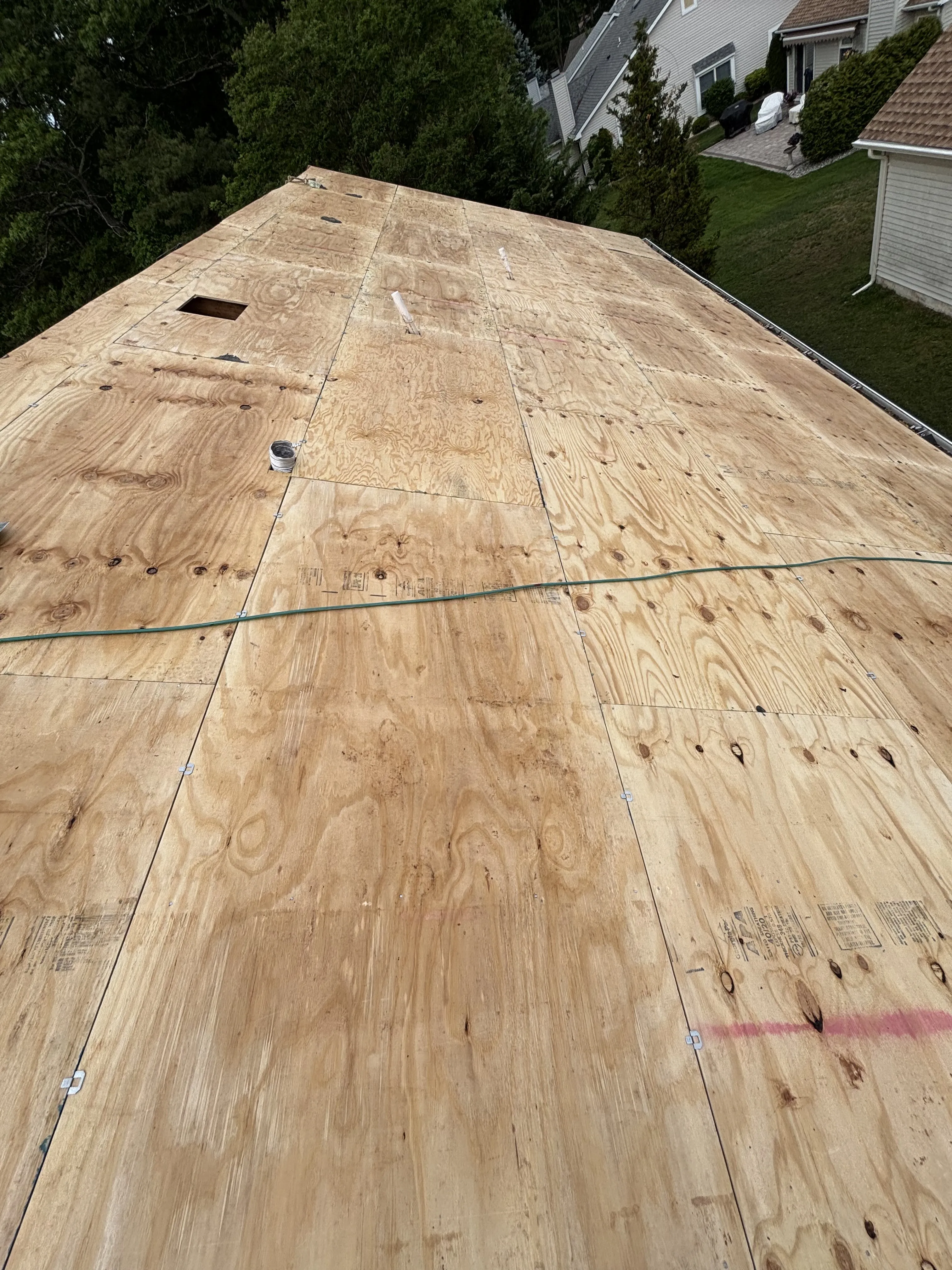 New plywood decking installed across the roof, fastened and ready for underlayment.