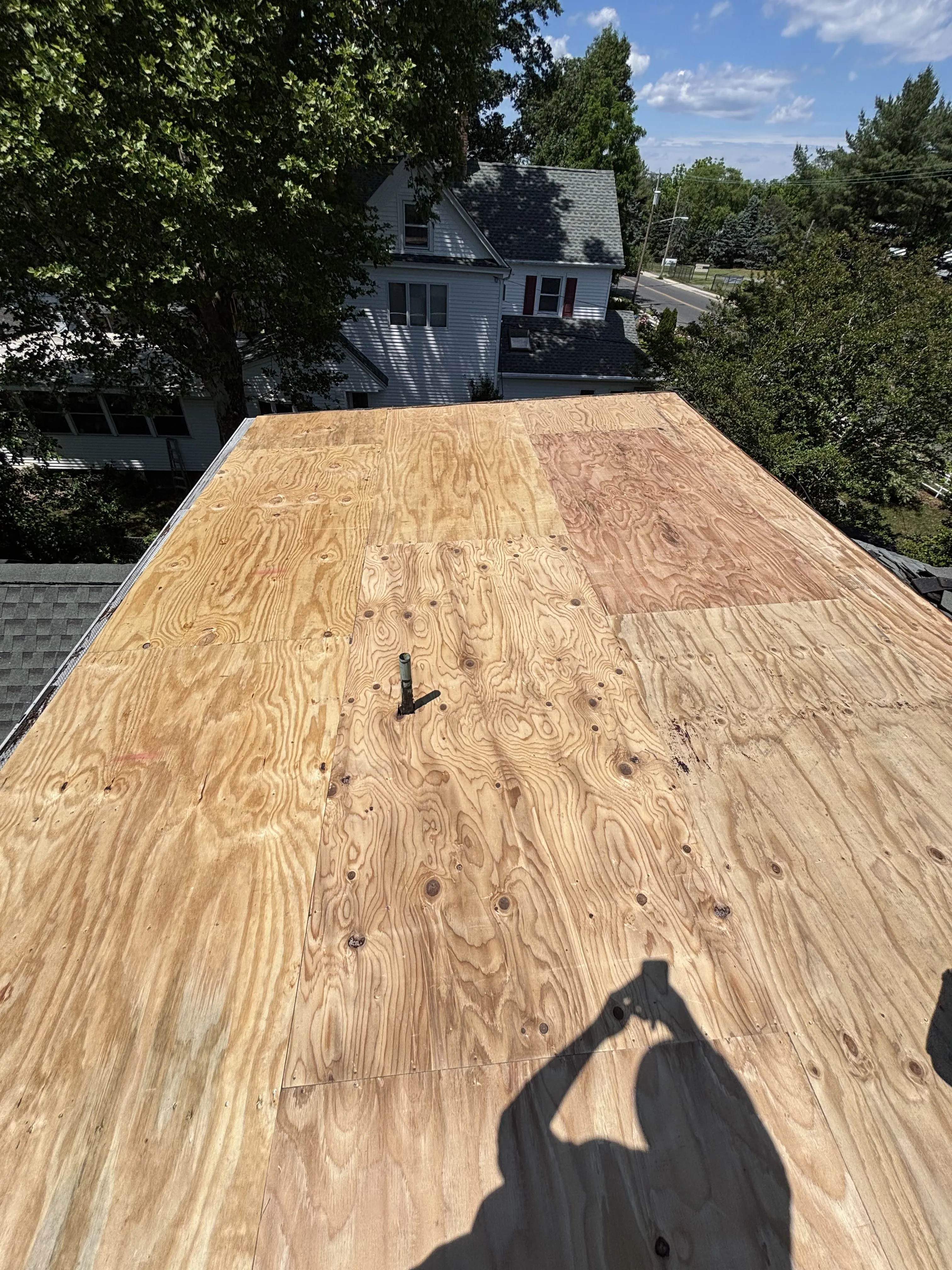 New plywood decking installed across the flat roof, replacing the damaged boards underneath.