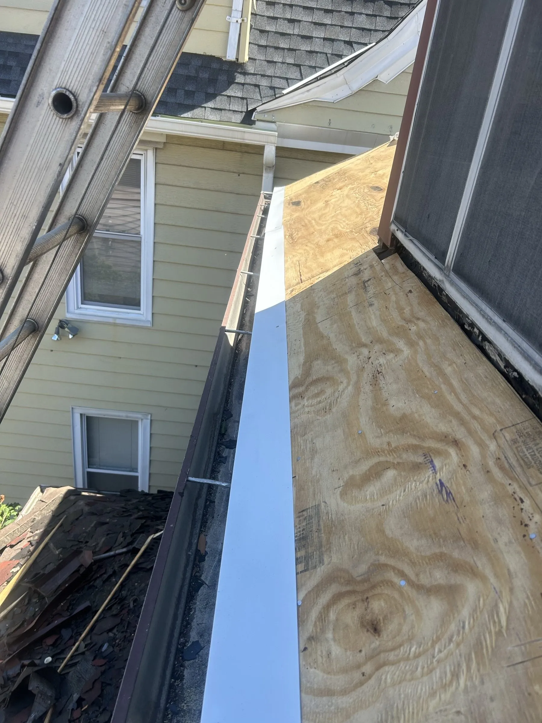 New plywood decking running up to the ridge in the narrow gap between two houses.