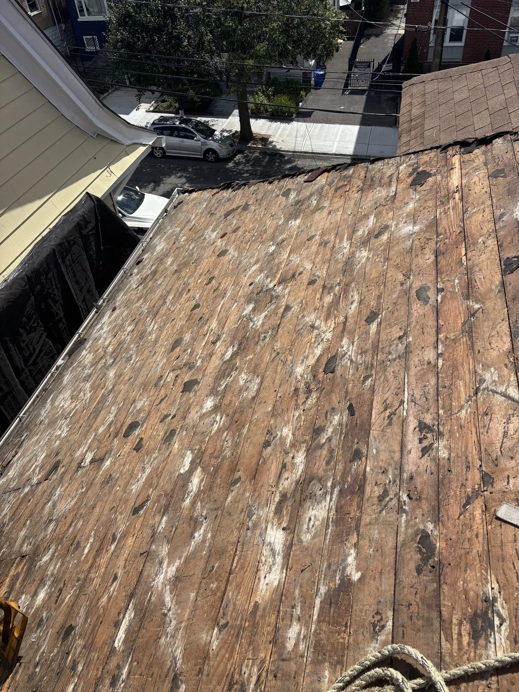 The worn original shingles running down the steep slope toward the street below.