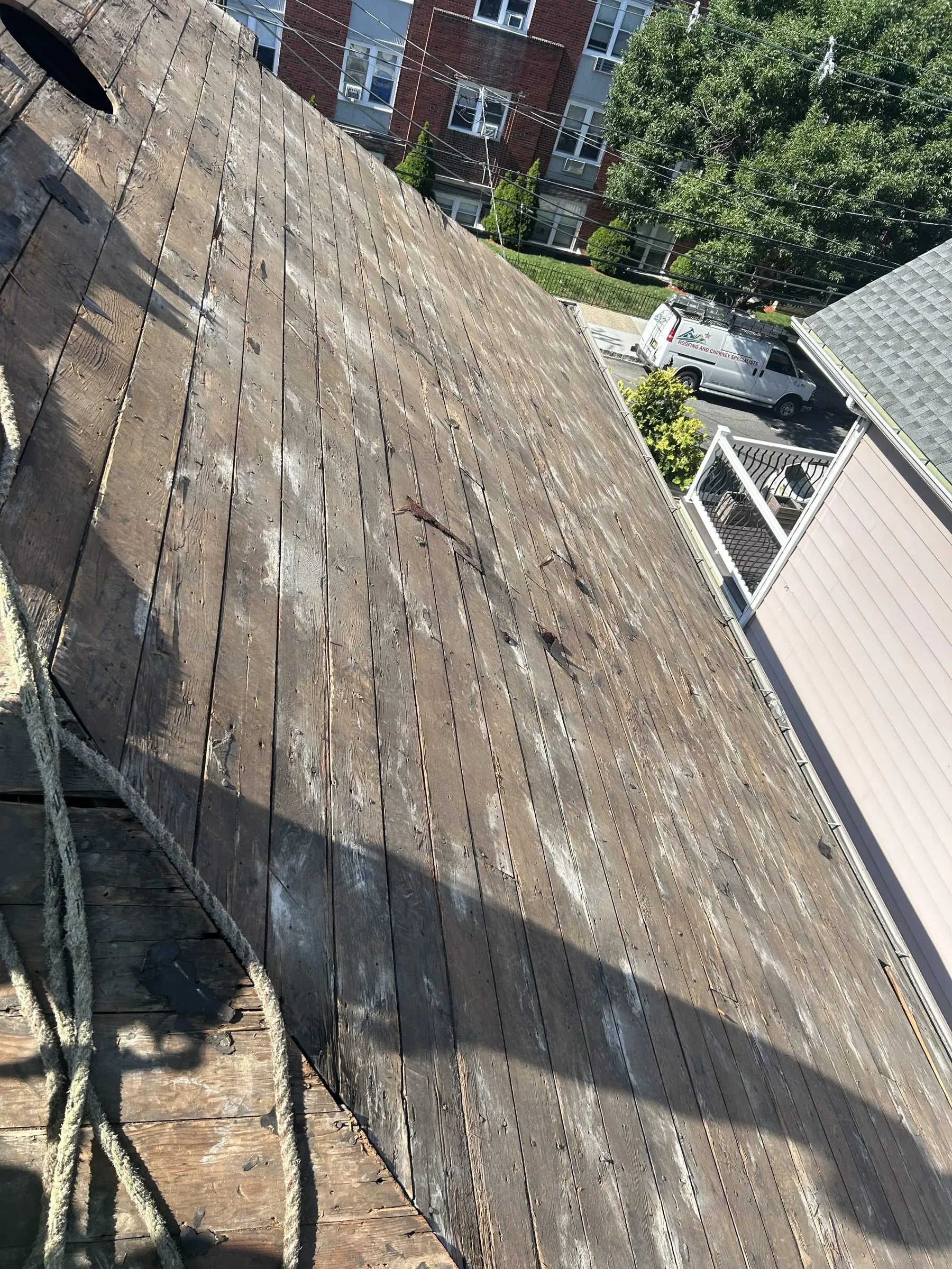 Old shingle layers pulled off the steep slope, exposing the original board decking.