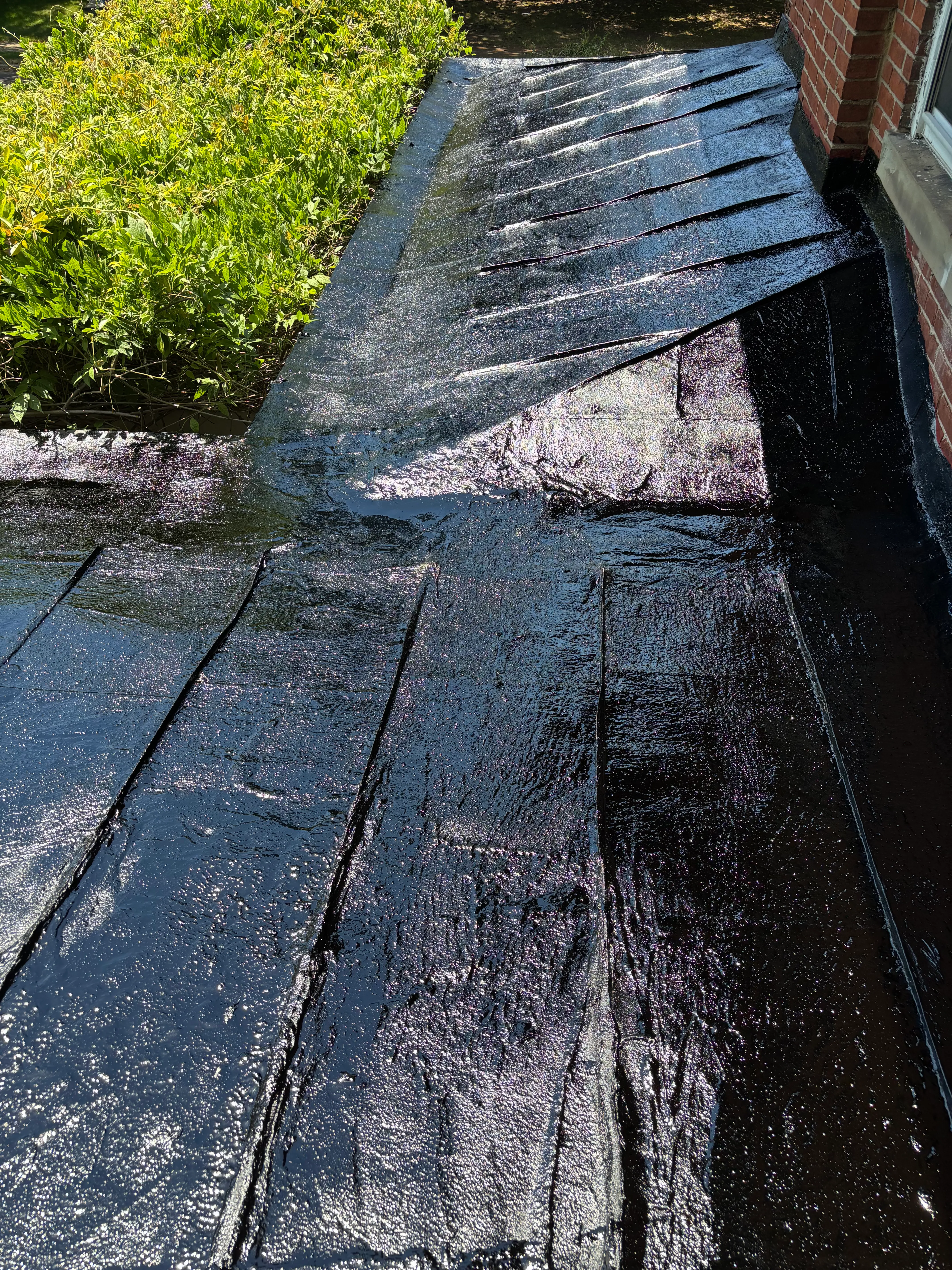 Finished glossy black coating wrapping the parapet corner and roof field after sealing and coating.