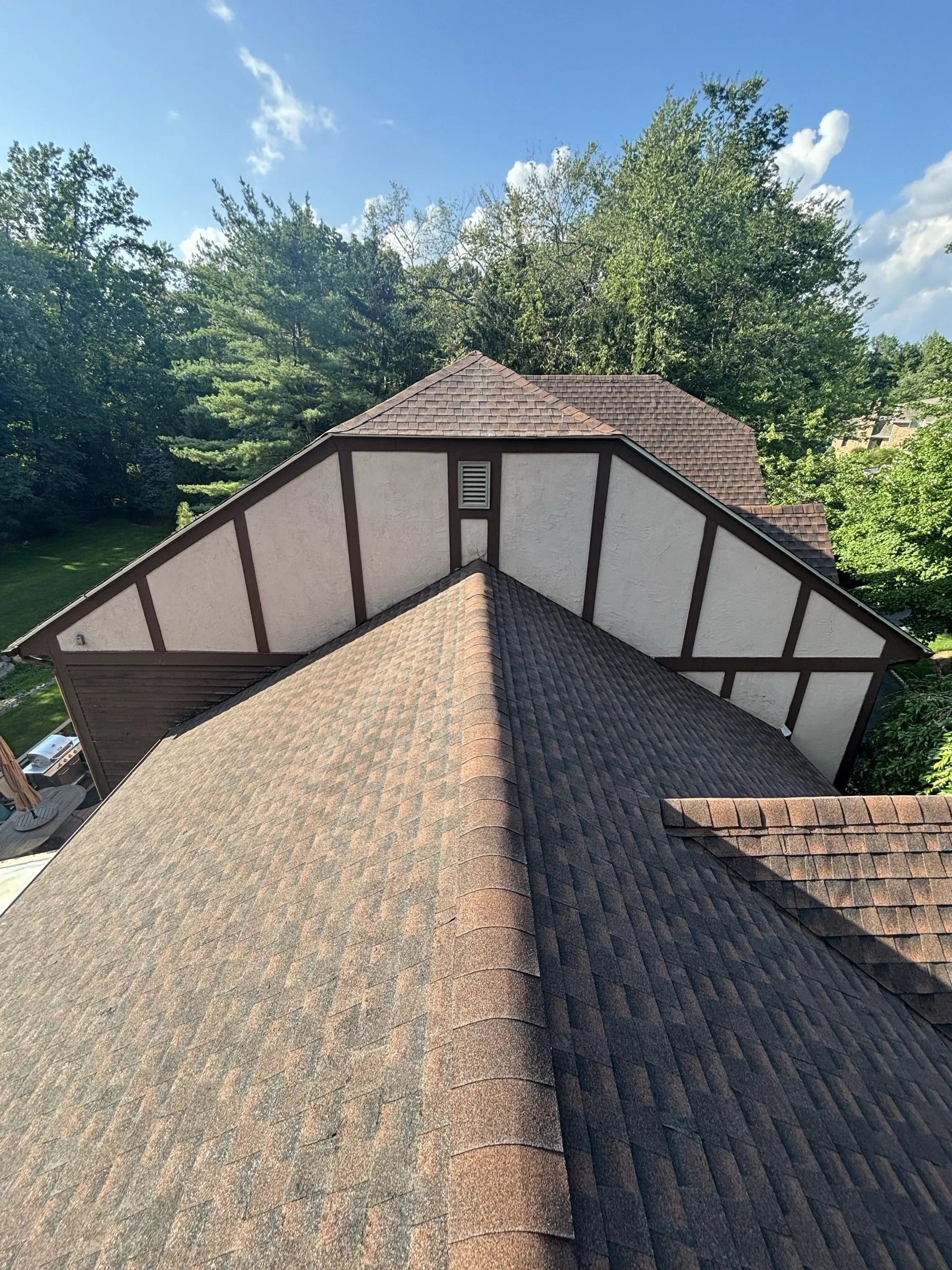 New shingles running down a long valley beside the half-timbered gable end.