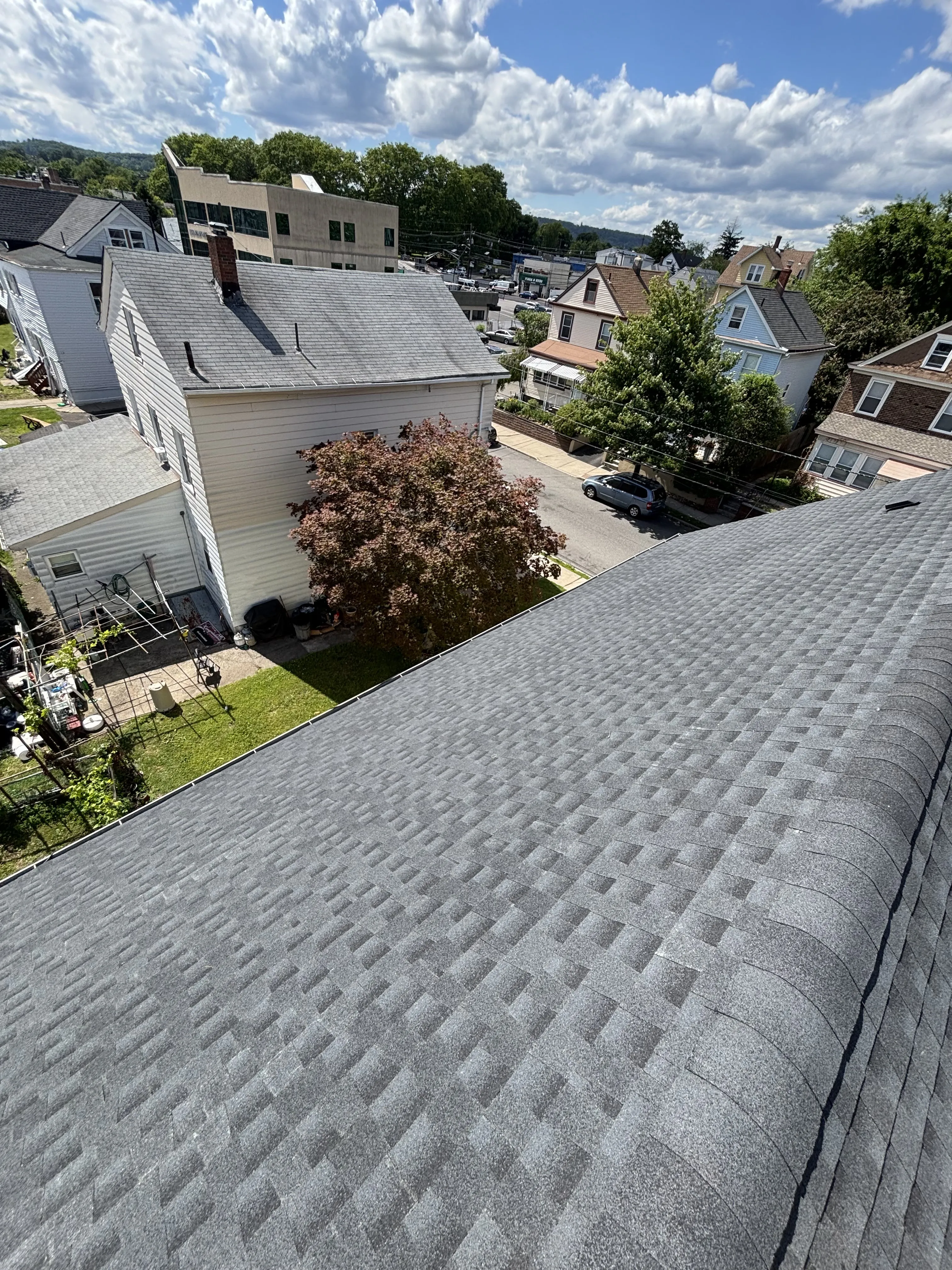 Finished GAF HDZ Charcoal shingle roof on the Clifton home, viewed across the slope toward the street.