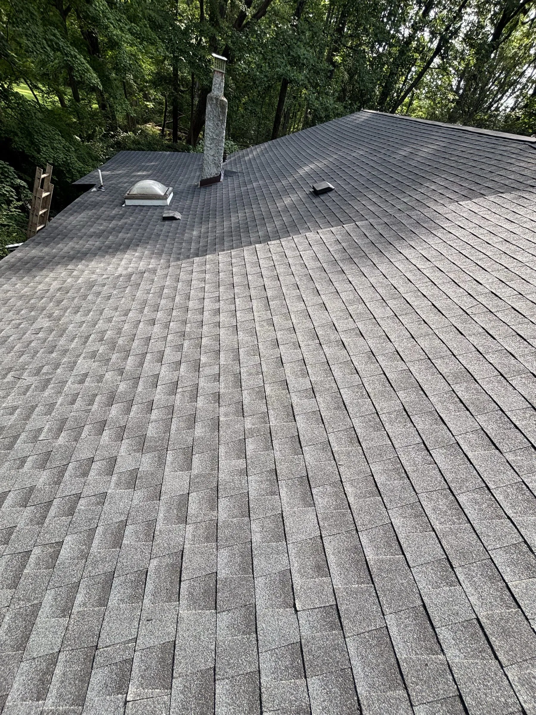 New shingles across the completed slope with a round vent near the ridge.