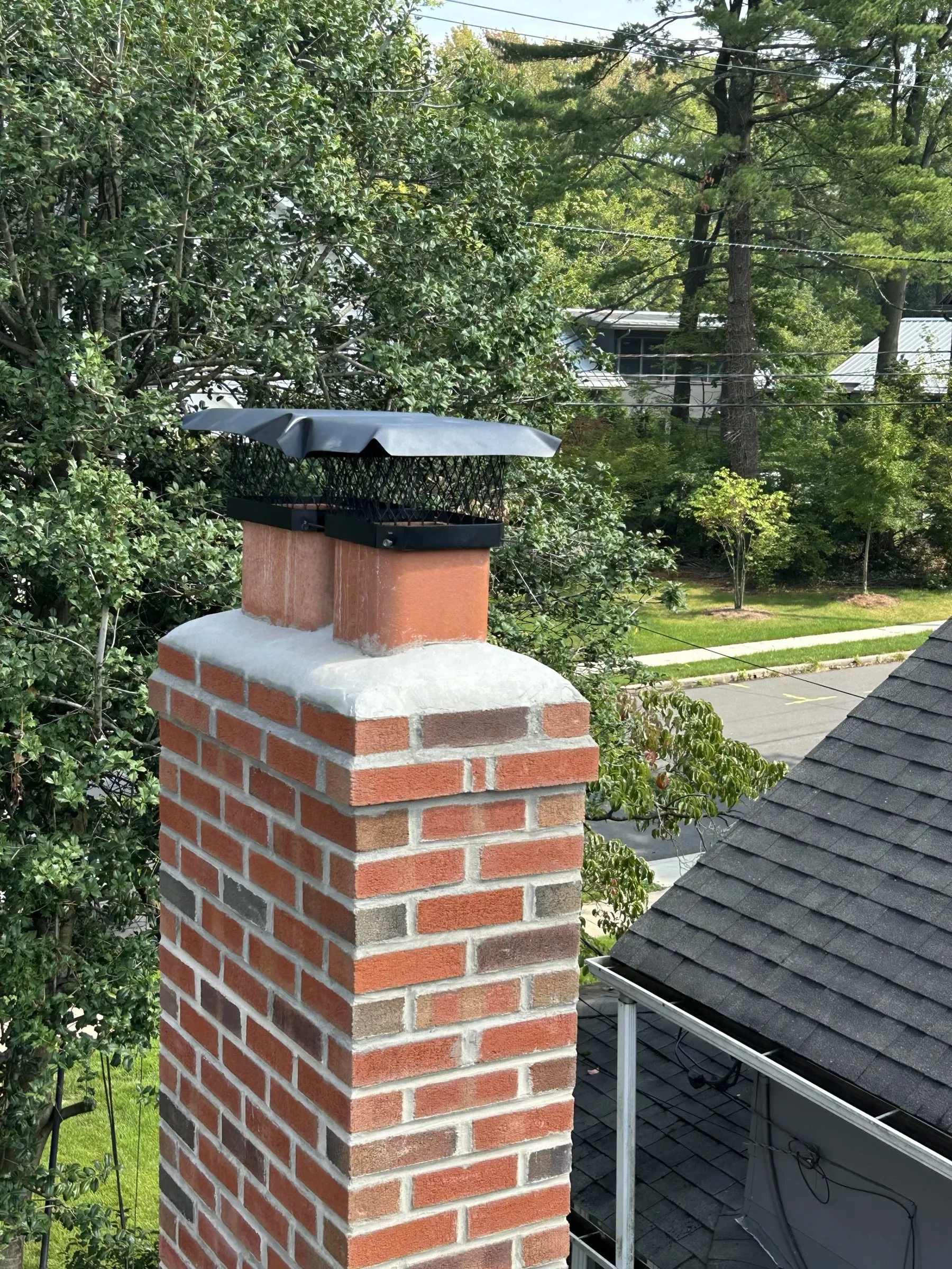 The completed chimney seen from the roof, new brickwork running up to the crown and cap.