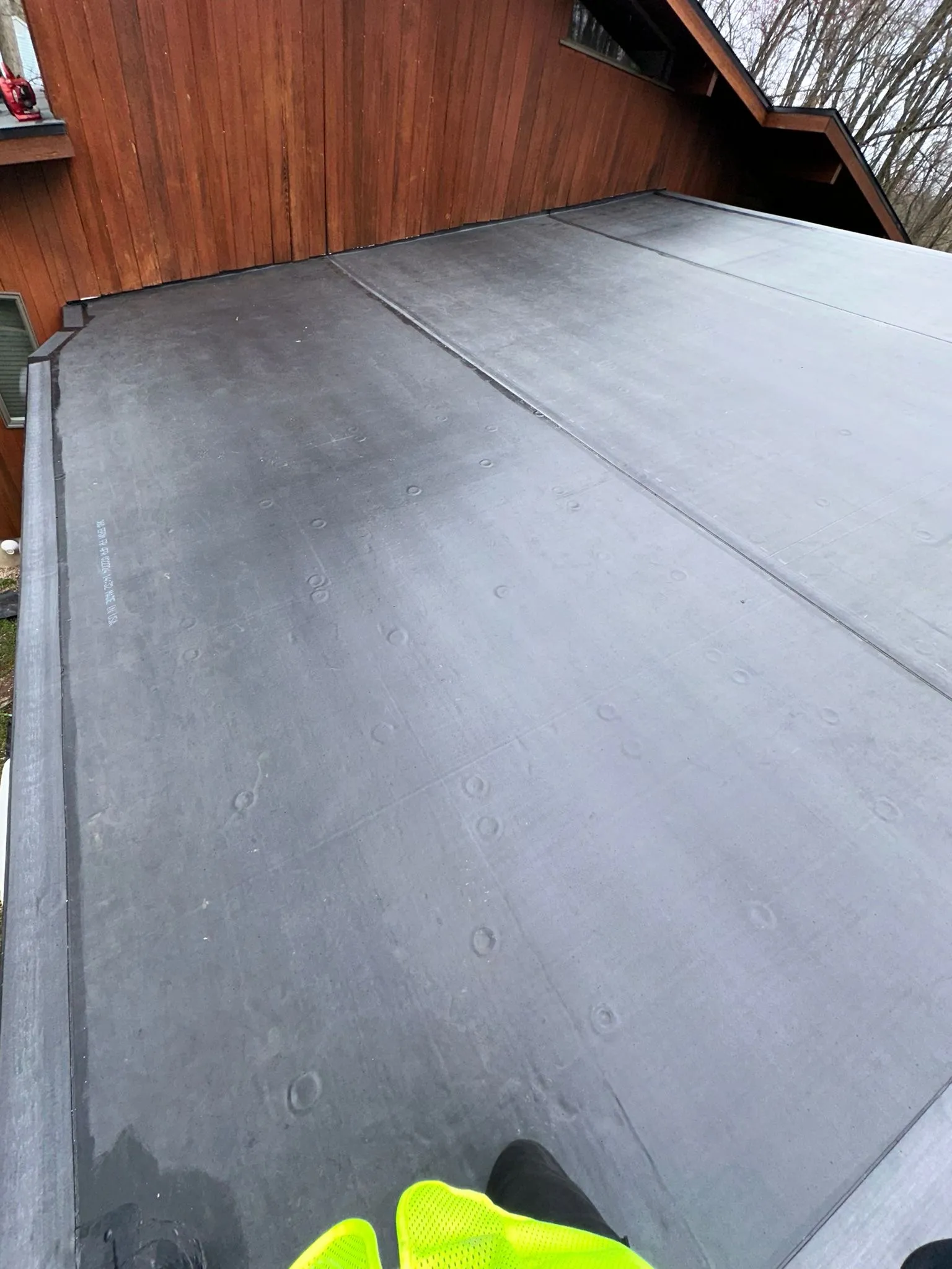Finished EPDM membrane meeting the home's cedar siding, the seams rolled clean and flat.