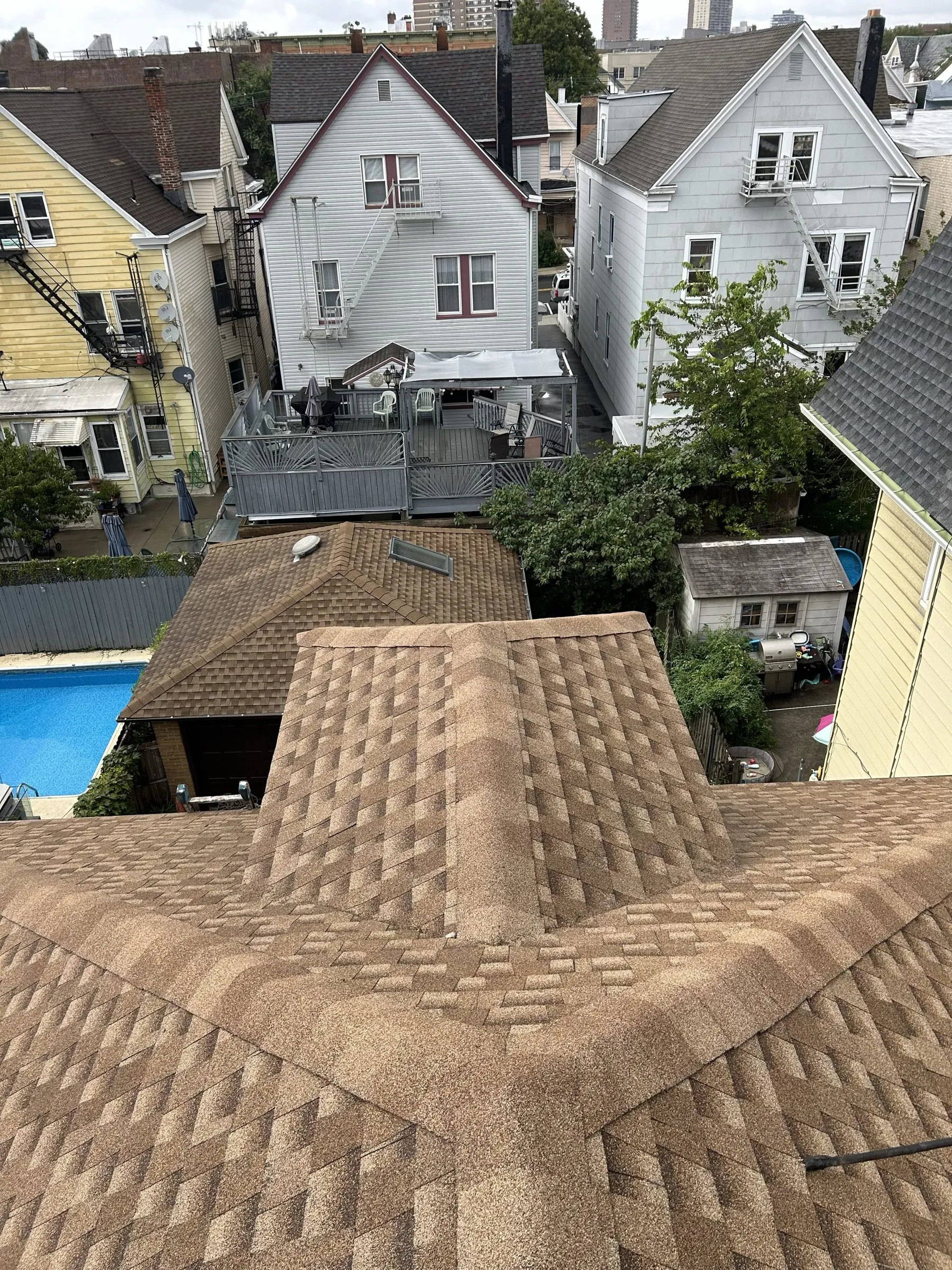 The completed roof seen from above, new shingles across the hip and down the slopes.
