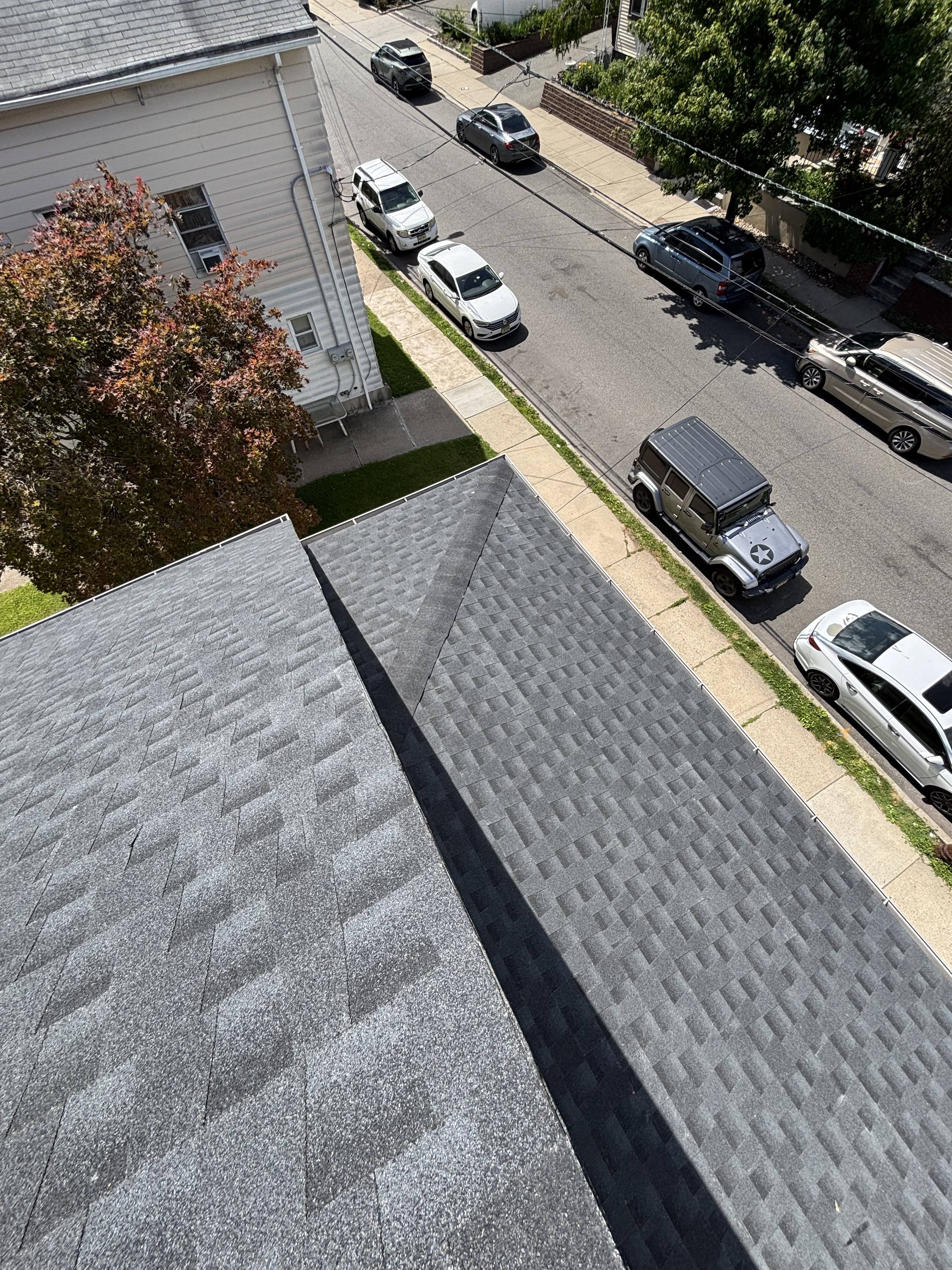 Completed GAF HDZ Charcoal shingle roof on the Clifton home, seen from above with crisp hip and valley lines over the street.