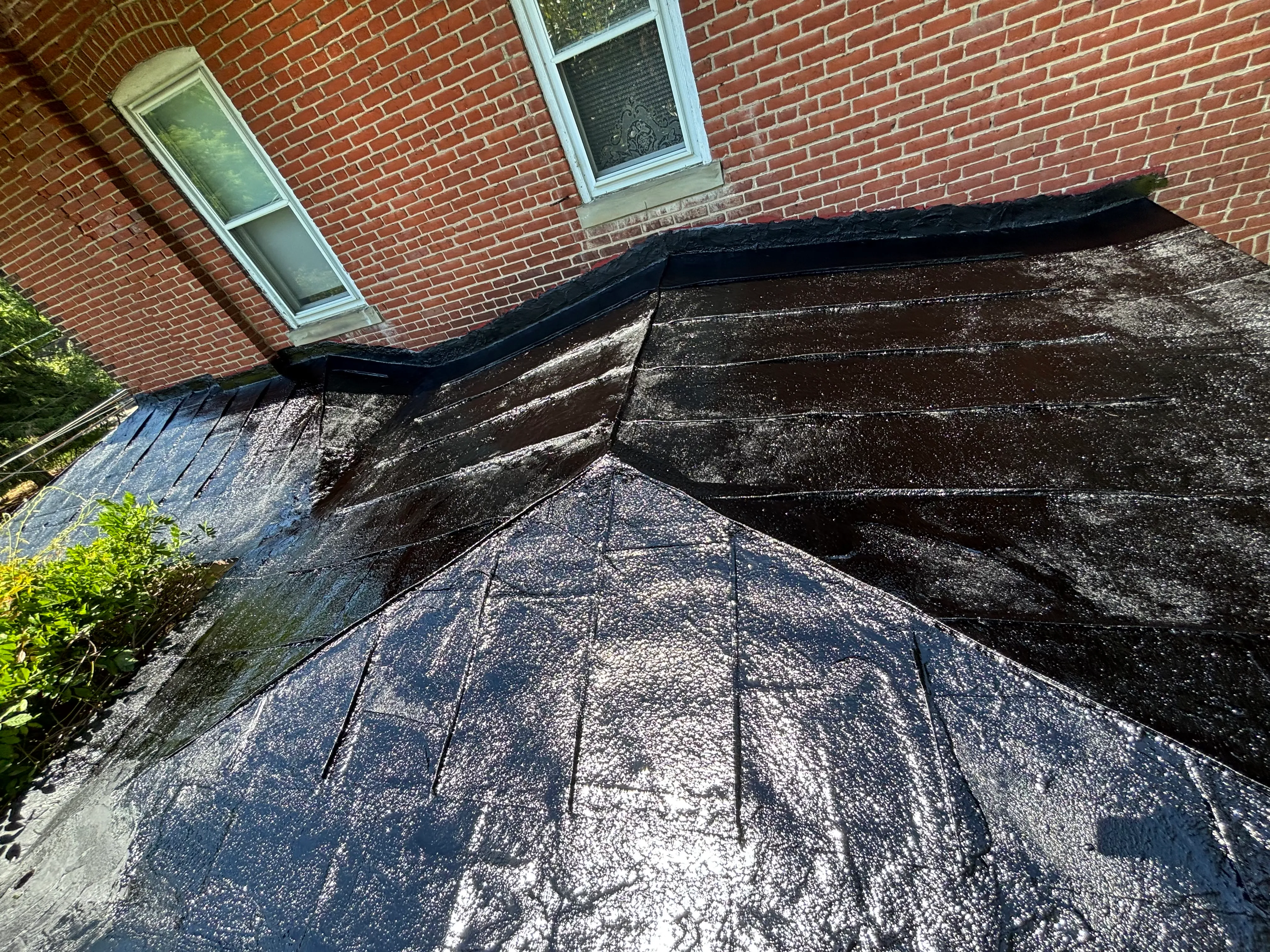 The same flat metal roof finished with a glossy black coating, seams sealed and the surface uniform.