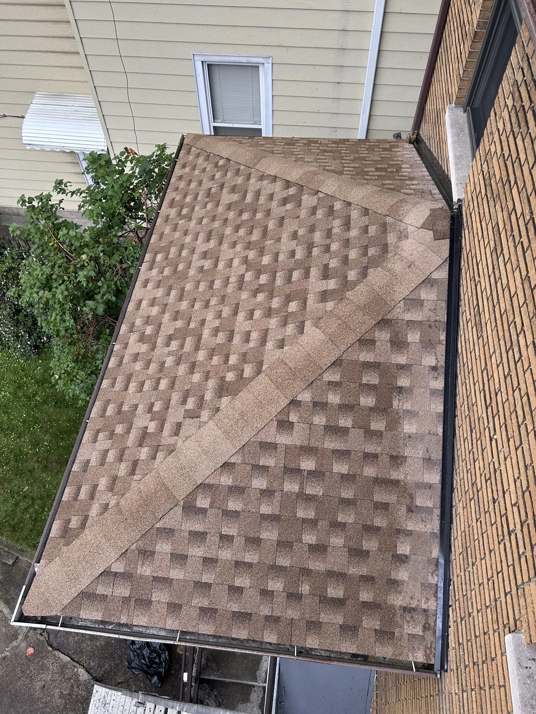 The finished shingle surface meeting the siding wall, new flashing along the join.