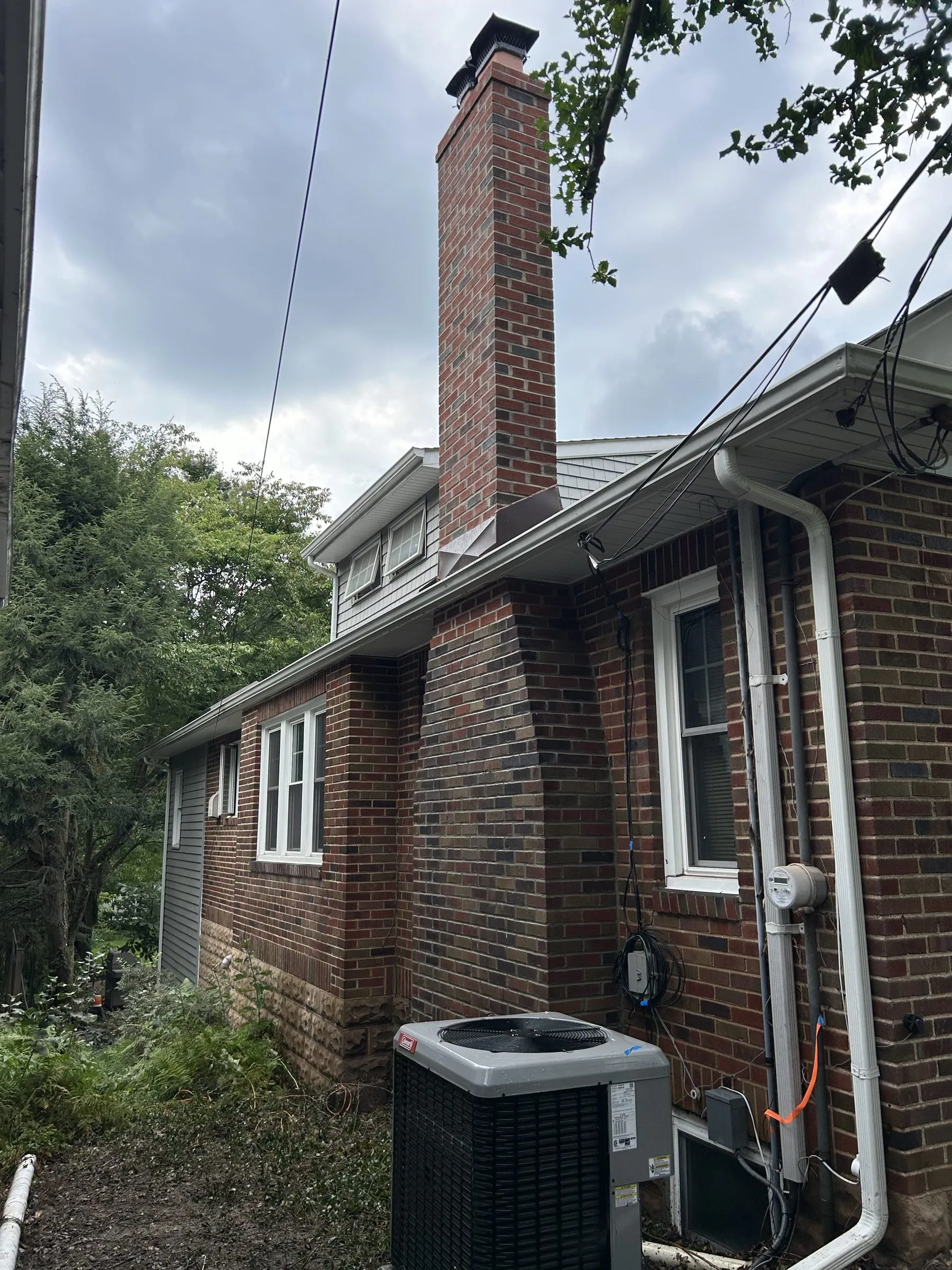 The rebuilt chimney on the side of the brick house, seen from the driveway below.