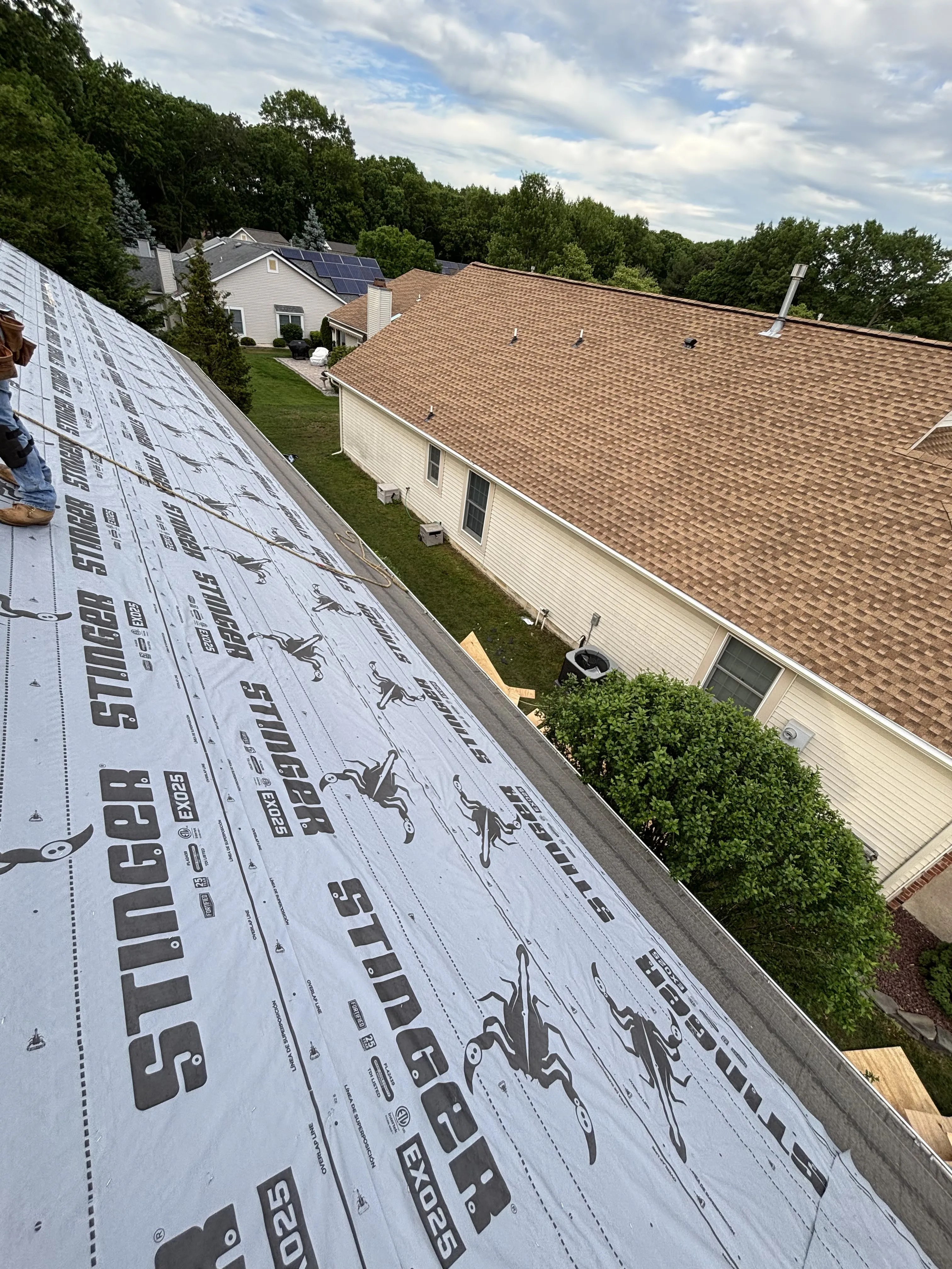 Synthetic underlayment rolled out and fastened over the new decking to weatherproof the roof before shingles.