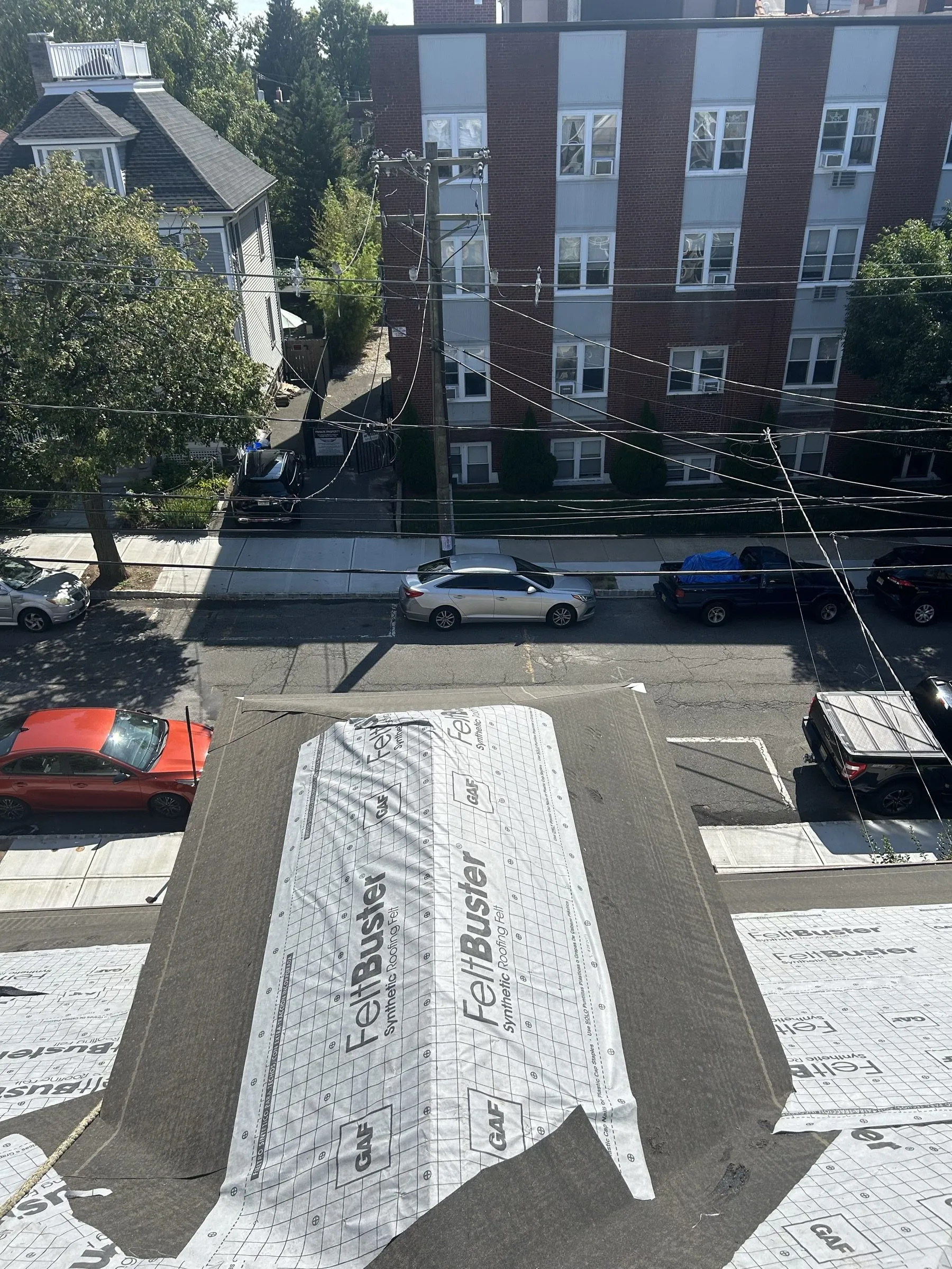 Underlayment and metal valley flashing running down the slope above the parked cars.