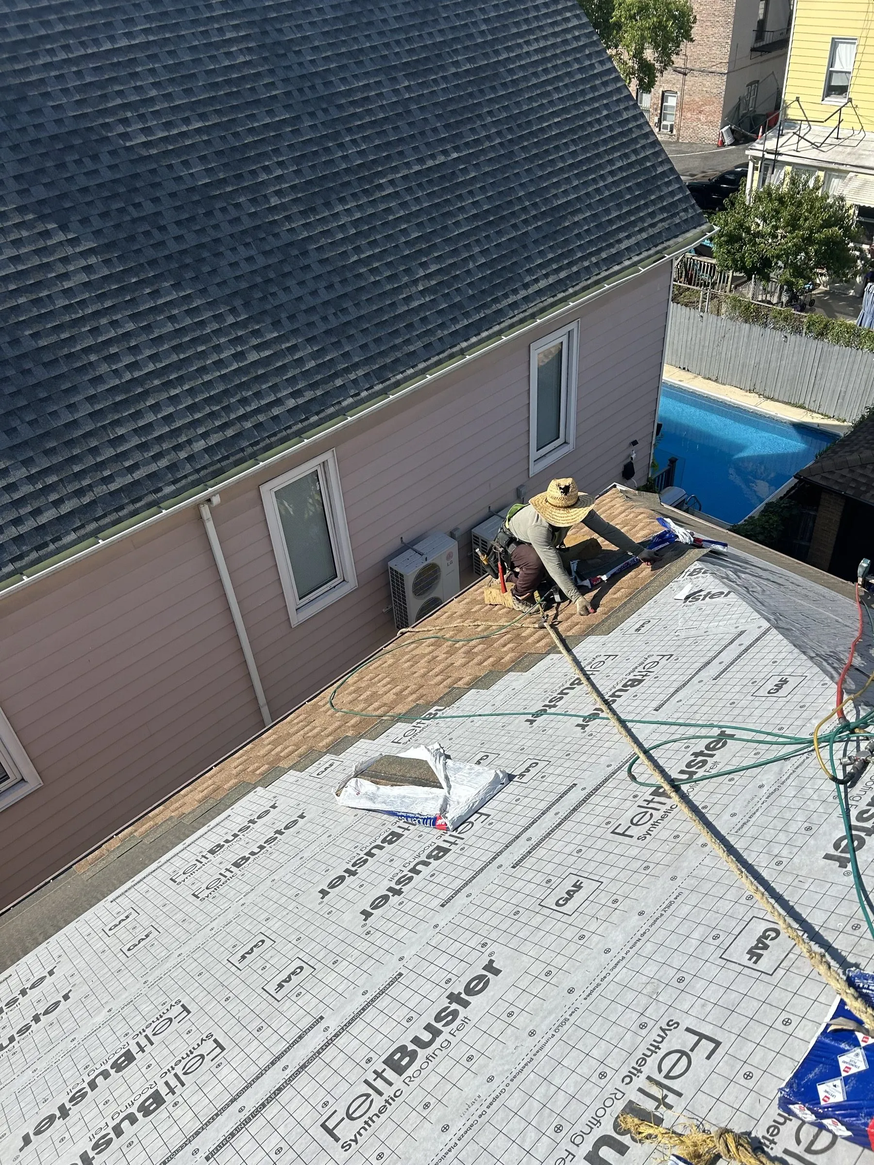 Underlayment laid up to the wall behind the chimney, materials staged on the slope.