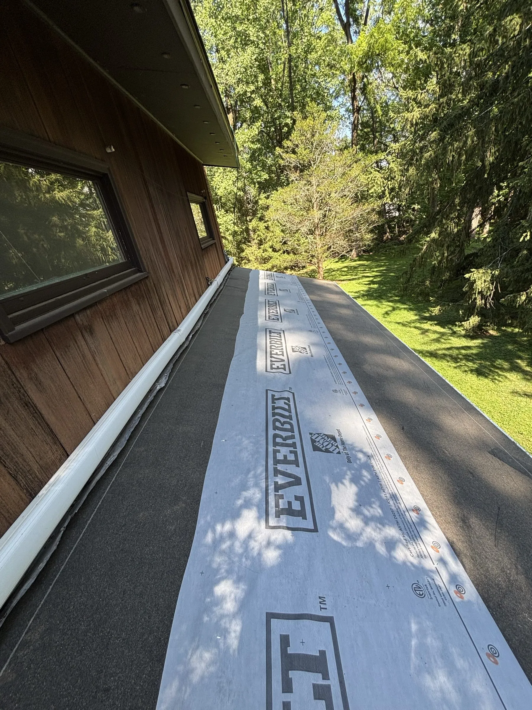 Underlayment and metal valley flashing running down the valley beside the dormer wall.