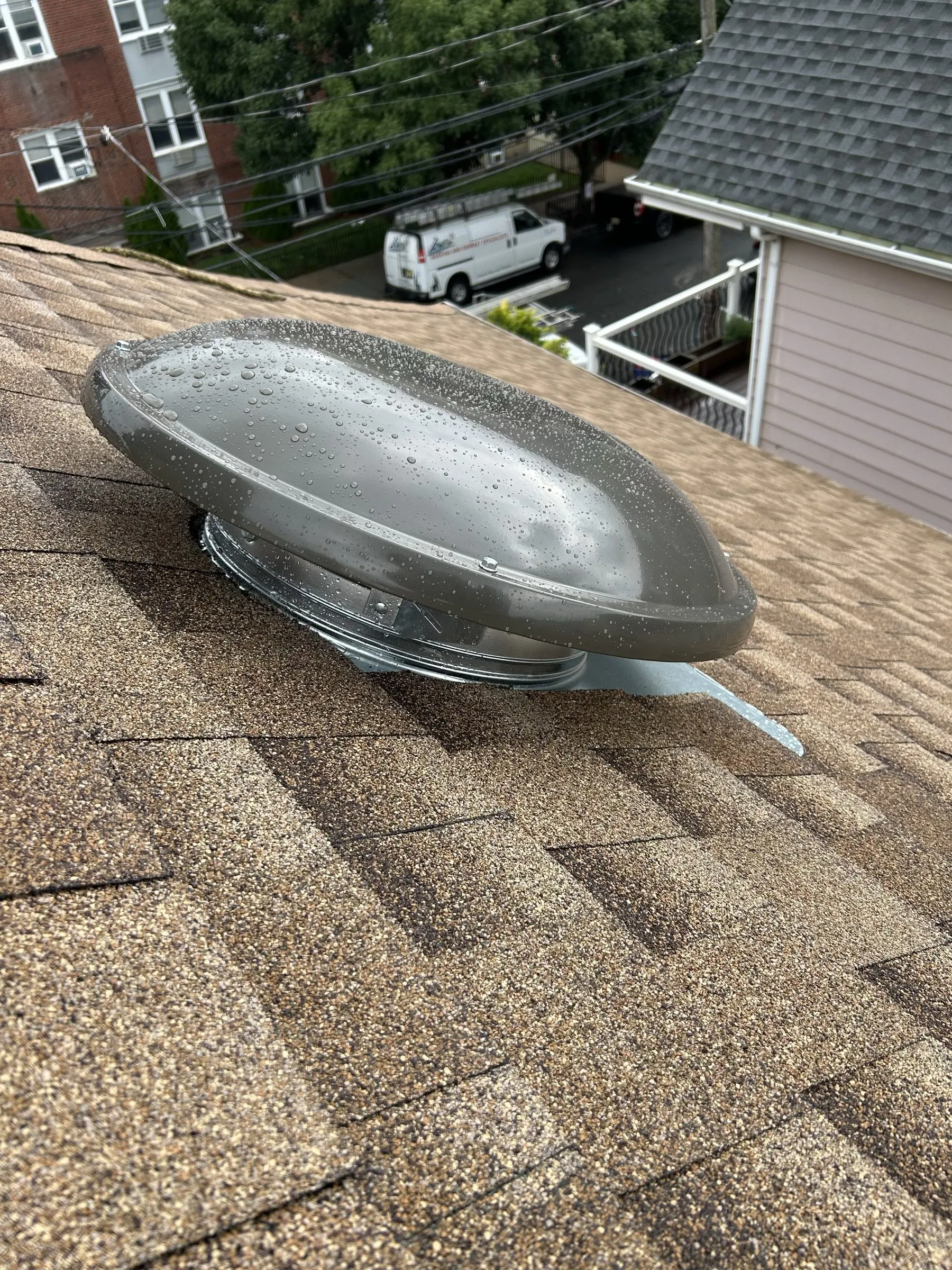 A new domed power vent set into the new shingles near the ridge.